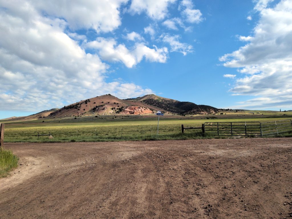 Open pasture with barbed-wire fence and the Bannock Range stretching south.